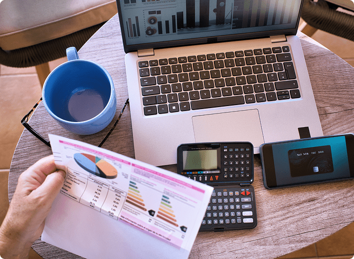 Laptop, charts, calculator, smartphone, and coffee mug.